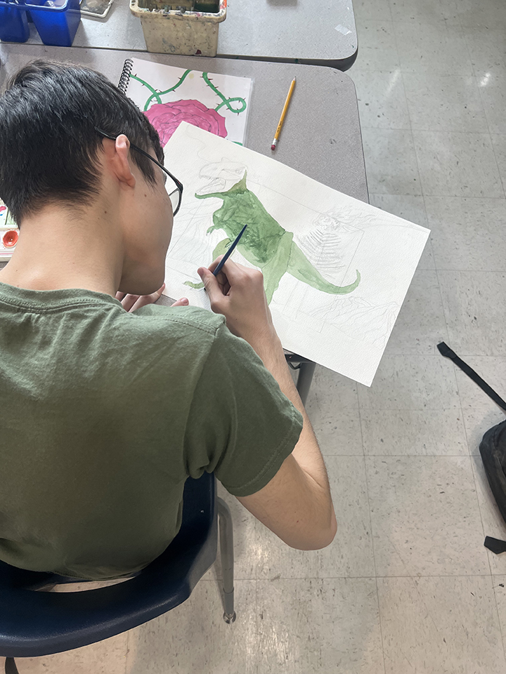 A teen boy sketches a T-rex
