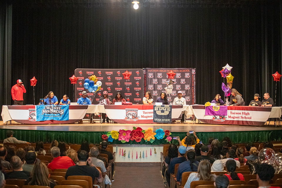Student athletes on stage signing their letters of intent