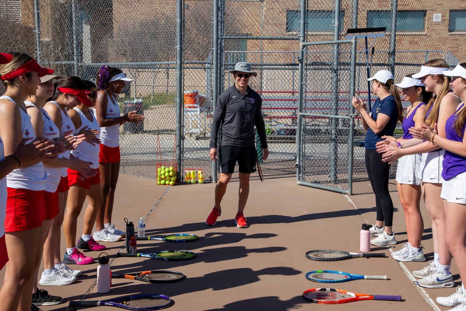 The THMS and Sabino girls tennis squads stand facing each other on the court